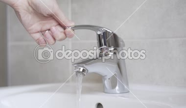 Su musluk açıldı ve su lavabo içine akar, tekrar durdu daha. Kadın el musluk ve su lavabo içine akar açın. Sonra yine suyu durdurur..