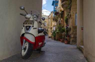 Malta 'da Rabat 'ın dar Sokağı. Küçük sokakta motosiklet, güzel çiçekler arka planda.