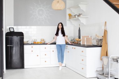 Modern mutfakta mutlu bir kadın. Modern mutfakta gülümseyen genç ev kadınının portresi.