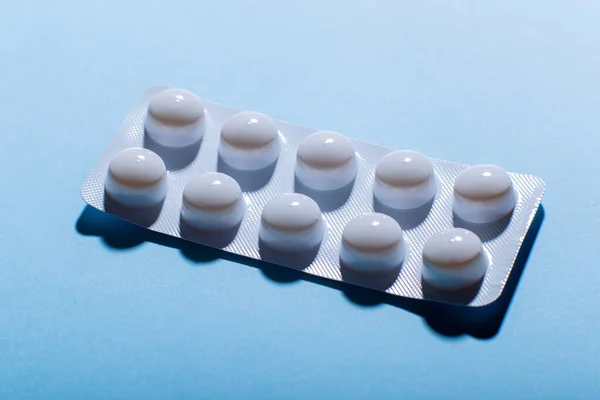 Close up pills in blister pack on blue background, pharmaceutical blister.