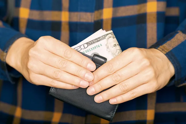 Hands holding dollars and small money pouch, close up