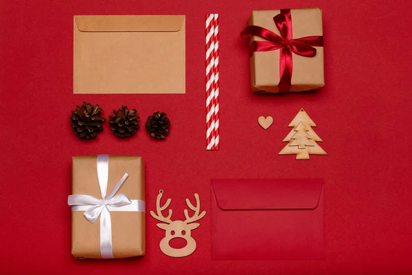 クリスマスの構図 クリスマスプレゼント 木製のおもちゃ 赤い背景の松のコーントップビュー — ストック写真