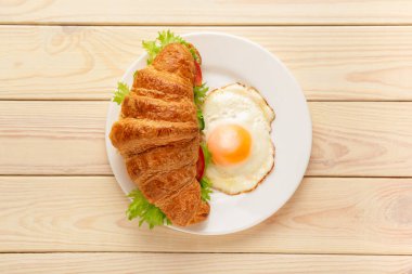 Ahşap arka planda kızarmış yumurtalı kruvasan sandviçi. Sağlıklı vejetaryen kahvaltısı