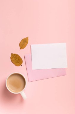 Sonbahar kompozisyonu, bir fincan kahve, kağıt boş, pembe pastel arka plan. Sonbahar konsepti. Düz yat, boşluğu kopyala.