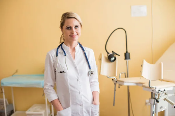 Mladá žena gynekolog stojící za křeslo — Stock fotografie