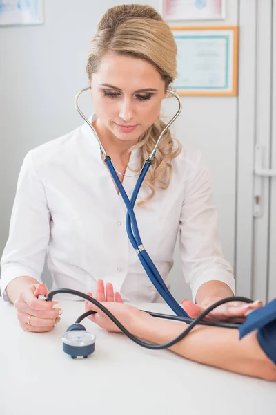 Доктор вимірює тиск вагітної. Лікар приймає кров'яний тиск пацієнта в офісі — стокове фото
