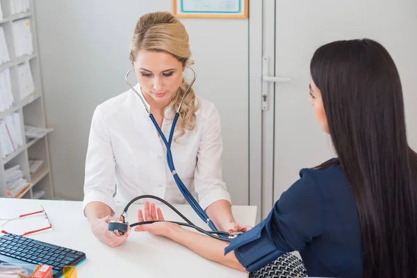 Dottore che misura la pressione della donna incinta. Medico che prende la pressione sanguigna della paziente in ufficio — Foto Stock