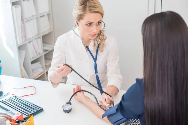 Dottore che misura la pressione della donna incinta. Medico che prende la pressione sanguigna della paziente in ufficio — Foto Stock