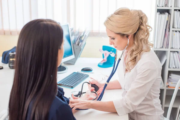 Dottore che misura la pressione della donna incinta. Medico che prende la pressione sanguigna della paziente in ufficio — Foto Stock