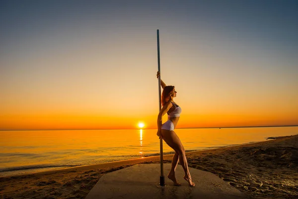 Athlétique fille se tient à côté d'un pylône portable sur la plage. Sable, coucher de soleil, plage . — Photo
