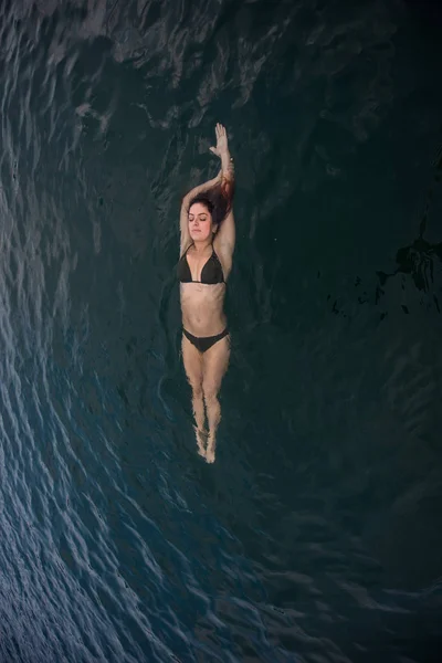 Mladá žena stojí ve vodě na zádech. Krásná žena v zelených bikinách leží na zádech ve vodě. — Stock fotografie