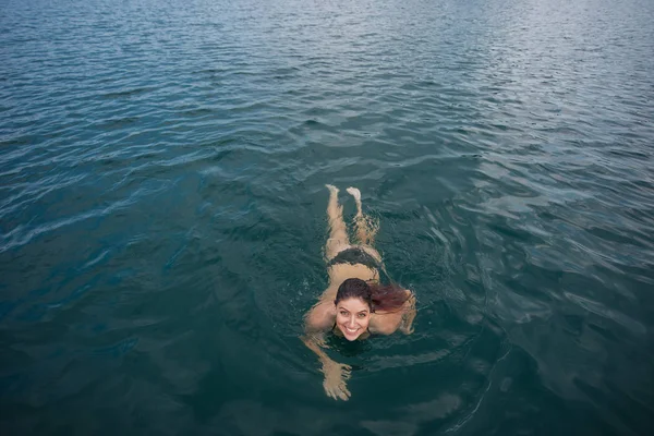 La jeune femme est allongée dans l'eau sur le dos. Belle femme dans un bikini vert nageant dans le lac — Photo