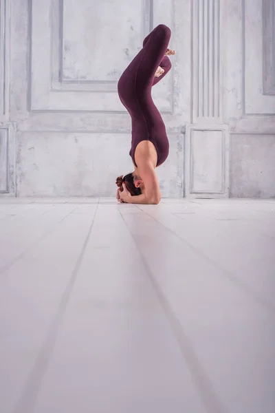 Una donna che medita in palestra. Giovane donna sportiva che fa pratica yoga su sfondo chiaro . — Foto Stock