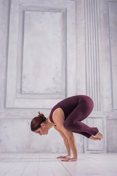 Kadın bir spor salonunda meditasyon. Sportif genç kadının açık renkli Yoga pratik yapması. Pratik yoga, Vinç alıştırmada, Bakasana poz duran genç çekici kadın — Stok fotoğraf