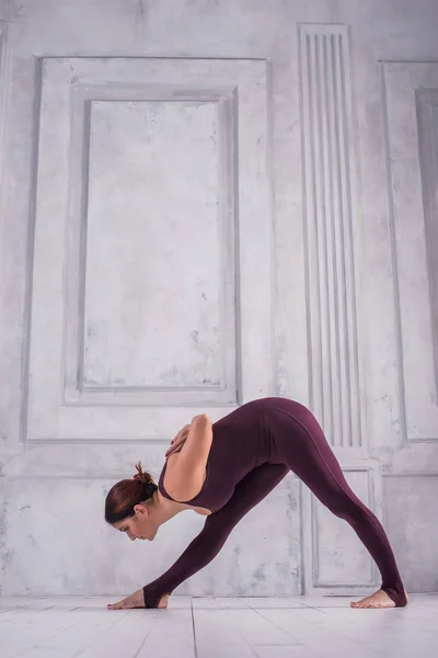 Kadın bir spor salonunda meditasyon. Sportif genç kadının açık renkli Yoga pratik yapması. Piramit veya tek taraflı kat poz elle geri, Parshvottanasana, tam uzunlukta arkasında — Stok fotoğraf