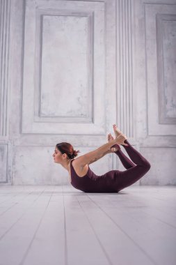 Sportif genç kadının Ashtanga Vinyasa Yoga asana Dhanurasana - yay poz yapması yerleştirmek. Sportif genç kadının açık renkli Yoga pratik yapması.