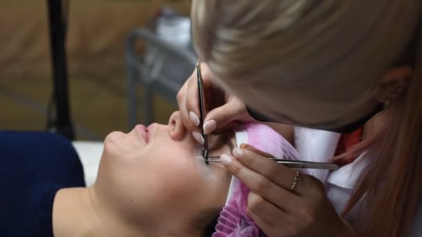 Professionelle Kosmetikerin, die sich einer Wimpernverlängerung unterzieht. Meister und Kunde in einem modernen Schönheitssalon — Stockvideo