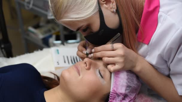 Professionell kosmetolog som genomgick ögonfrans förlängning förfarande. Master och en klient i en modern skönhetssalong — Stockvideo