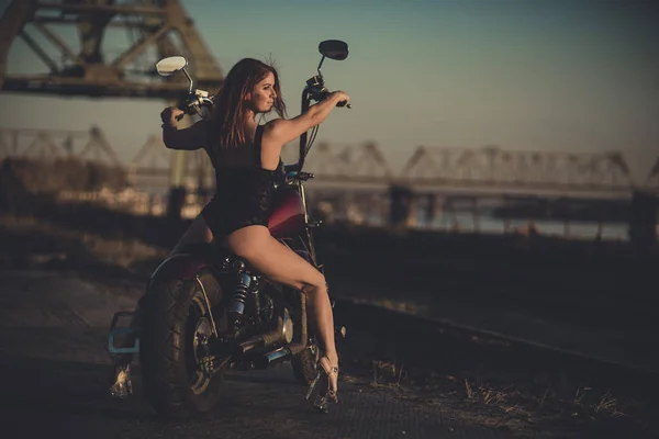 Rothaarige Frau in sexy Dessous in High Heels sitzt auf einem Motorrad. Attraktives rothaariges Mädchen sitzt bei Sonnenuntergang auf einem Motorrad — Stockfoto