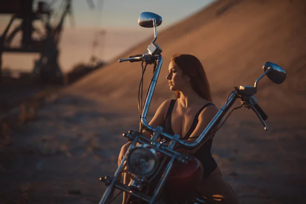 Rothaarige Frau in sexy Dessous in High Heels sitzt auf einem Motorrad. Attraktives rothaariges Mädchen sitzt bei Sonnenuntergang auf einem Motorrad — Stockfoto