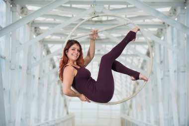 Bir spor Combo kırmızı saçlı hava jimnastikçi bir yaya geçidinde hava çemberinde gerçekleştirir.