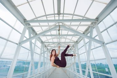 Bir spor Combo kırmızı saçlı hava jimnastikçi bir yaya geçidinde hava çemberinde gerçekleştirir.