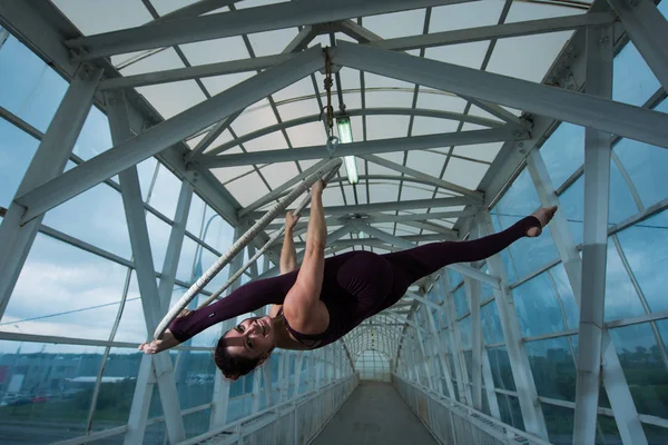 Una ginnasta dell'aria fa una spaccatura russa su un cerchio sospeso su una capriata metallica. attrice circo sul ring arioso . — Foto Stock