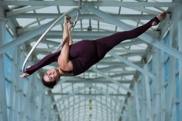 Un gymnaste aérien fait une fente russe sur un cerceau d'air suspendu sur une poutre métallique. actrice de cirque sur l'anneau aéré . — Photo