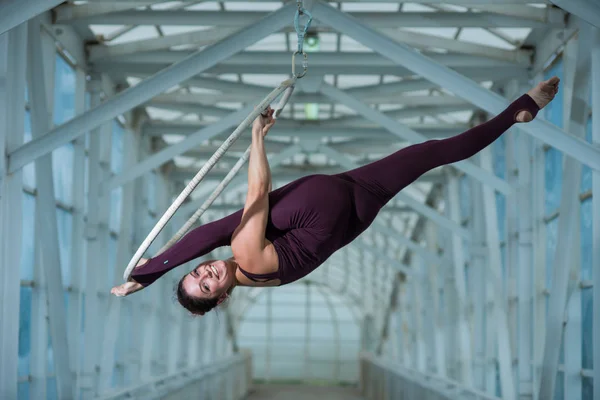 Un gymnaste aérien fait une fente russe sur un cerceau d'air suspendu sur une poutre métallique. actrice de cirque sur l'anneau aéré . — Photo