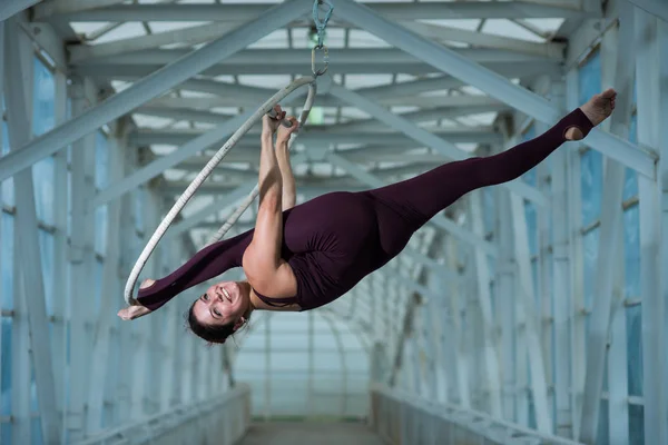 Un gymnaste aérien fait une fente russe sur un cerceau d'air suspendu sur une poutre métallique. actrice de cirque sur l'anneau aéré . — Photo