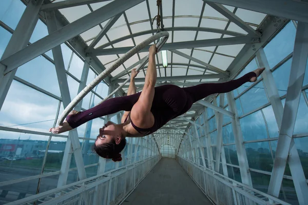 Un gymnaste aérien fait une fente russe sur un cerceau d'air suspendu sur une poutre métallique. actrice de cirque sur l'anneau aéré . — Photo