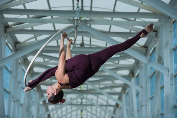 Un gymnaste aérien fait une fente russe sur un cerceau d'air suspendu sur une poutre métallique. actrice de cirque sur l'anneau aéré . — Photo