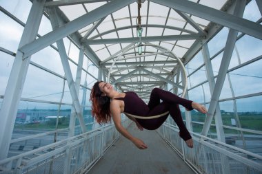 Bir spor Combo kırmızı saçlı hava jimnastikçi bir yaya geçidinde hava çemberinde gerçekleştirir. 