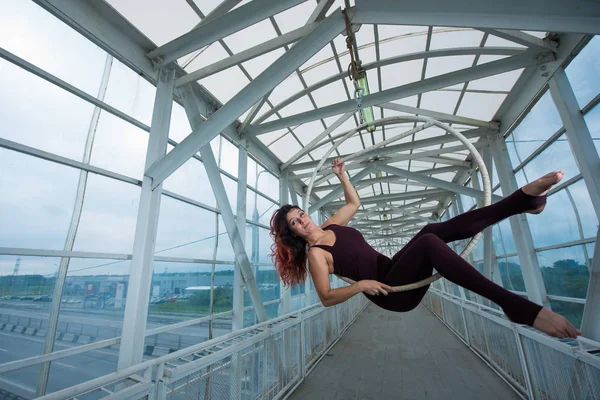 Bir spor Combo kırmızı saçlı hava jimnastikçi bir yaya geçidinde hava çemberinde gerçekleştirir. — Stok fotoğraf