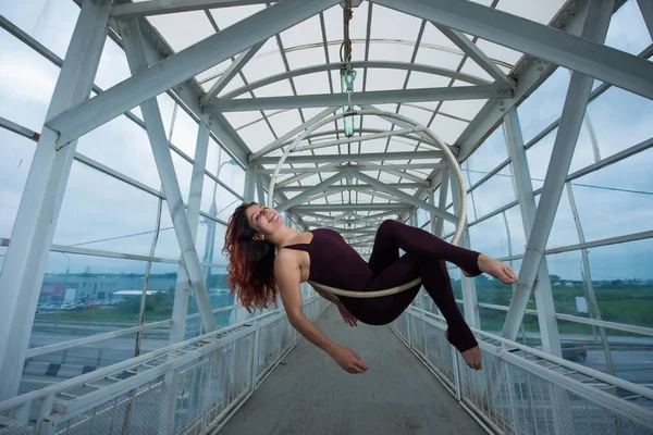 Bir spor Combo kırmızı saçlı hava jimnastikçi bir yaya geçidinde hava çemberinde gerçekleştirir. 