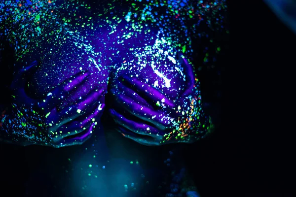 Corpo ultravioletto arte blu cielo notturno con stelle. Pittura fluorescente su un grande seno femminile coperto di mani . — Foto Stock