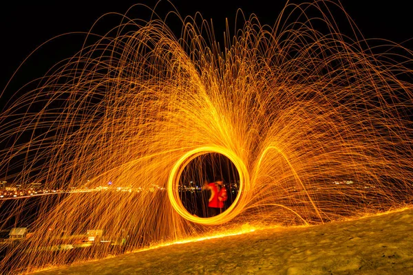 Large round burning fireworks sparkle from the burning steel wool. The city lights at night. — Stock Photo, Image