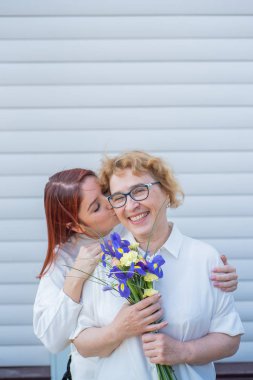 Yetişkin kızı evin avluda, dışında annesine çiçek verir. Birlikte vakit geçiriyoruz, hafta sonları evde kutlama lar. Anneler Günü. Sıcak kuşaklar arası ilişkiler
