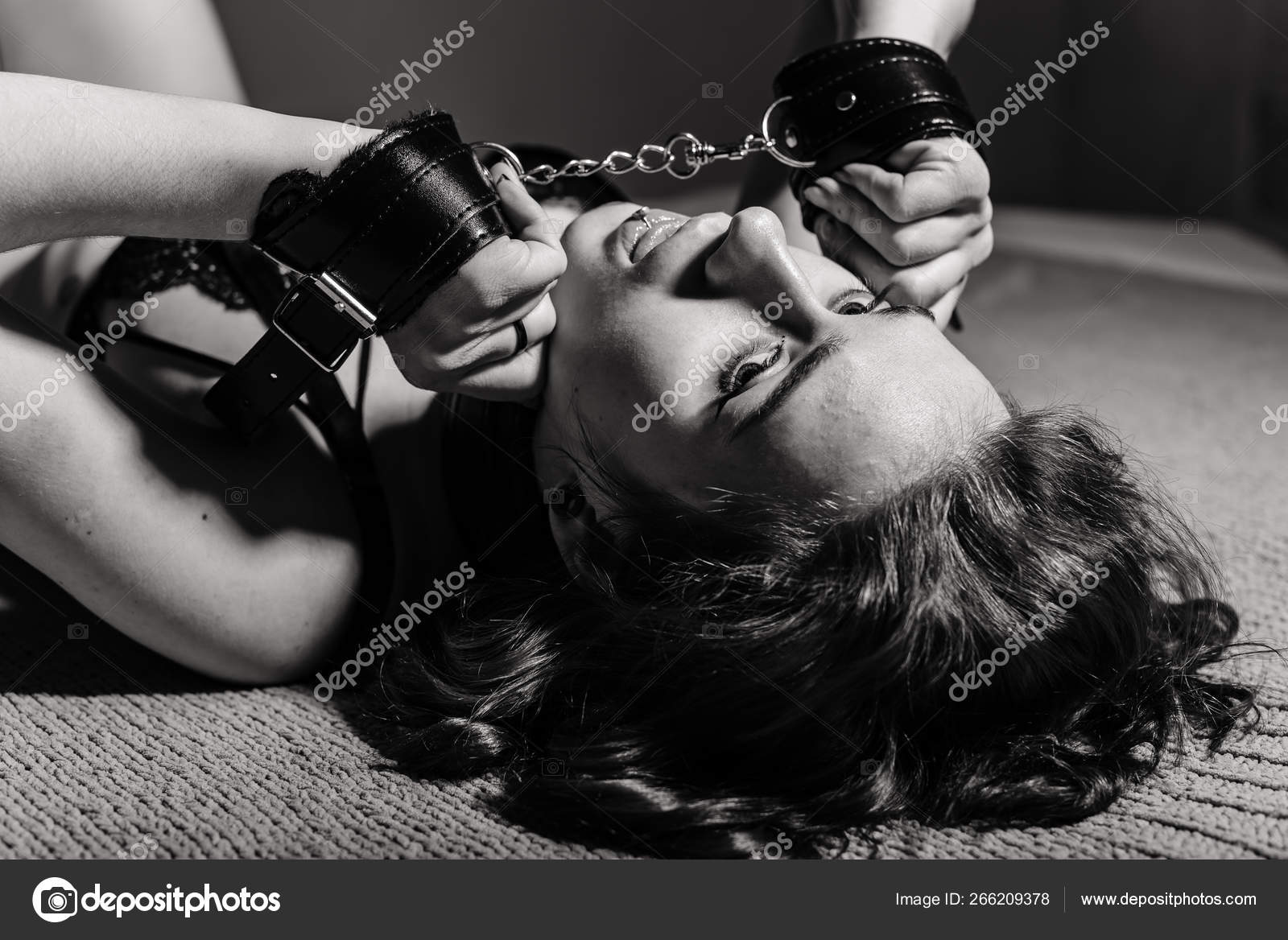 Молодая девушка в сексуальном белье, лежащая на кровати в наручниках. БДСМ  игры и развлечения. Сексуальное извращение . стоковое фото ©inside-studio  266209378