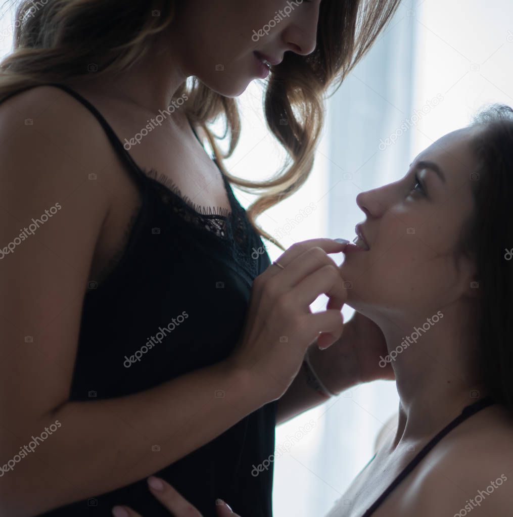The girl touches her lips with her fingers and her friend's mouth in her underwear.