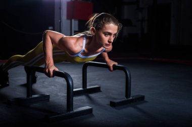 Spor salonunda barlar ile yatay şınav yapıyor sarı sıkı spor üniformagenç atletik kız