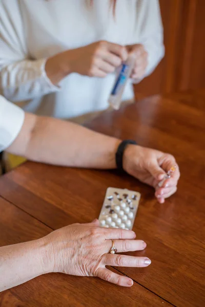 Elderly woman holds pills and ampoule. Close-up of pensioner's hands with drugs. Young woman unpacks the syringe. Daughter is going to give an injection to an elderly mother — Stock Photo, Image