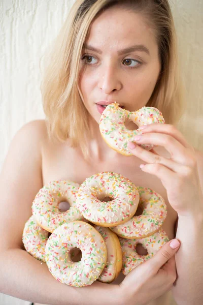 Jeune femme nue mangeant des beignets. Portrait d'une jolie femme avec une montagne de beignets — Photo