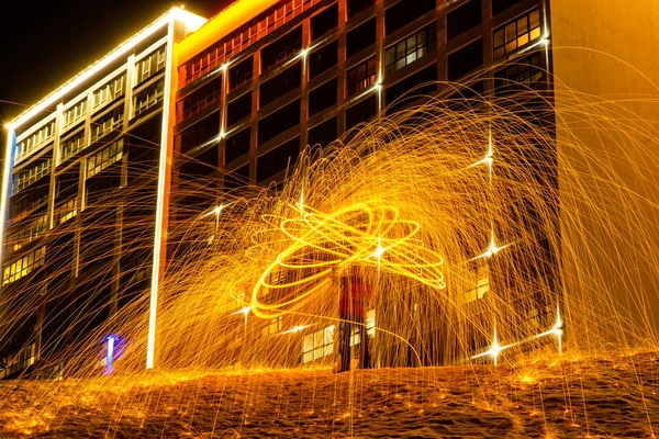 불타는 강철 양모에서 큰 둥근 불타는 불꽃이 반짝입니다. 밤에 는 도시의 불빛. — 스톡 사진