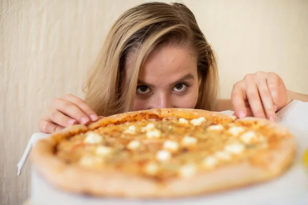 Portret van een vrouw die pizza eet. Mooie jonge vrouw in zwart ondergoed eten pizza — Stockfoto