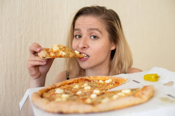 Portret van een vrouw die pizza eet. Mooie jonge vrouw in zwart ondergoed eten pizza — Stockfoto