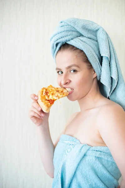 Linda chica con una toalla en la cabeza come pizza en la cama. Retrato de una joven comiendo comida rápida en la cama. Bodypositive — Foto de Stock