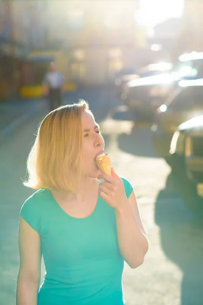 Портрет милої дівчини в зеленій сукні ходить на подвір'ї і їсть морозиво. Красива блондинка їсть десерт на вулиці в прекрасний літній день. Життя це приємна відпустка — стокове фото