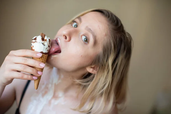 Sexy bionda lecca un cono cialda. Il gelato si sta sciogliendo, drenando eroticamente attraverso il corpo di una donna attraente. Bella ragazza spalmata di gelato. — Foto Stock