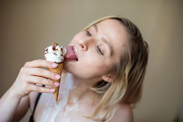 Sexy bionda lecca un cono cialda. Il gelato si sta sciogliendo, drenando eroticamente attraverso il corpo di una donna attraente. Bella ragazza spalmata di gelato. — Foto Stock
